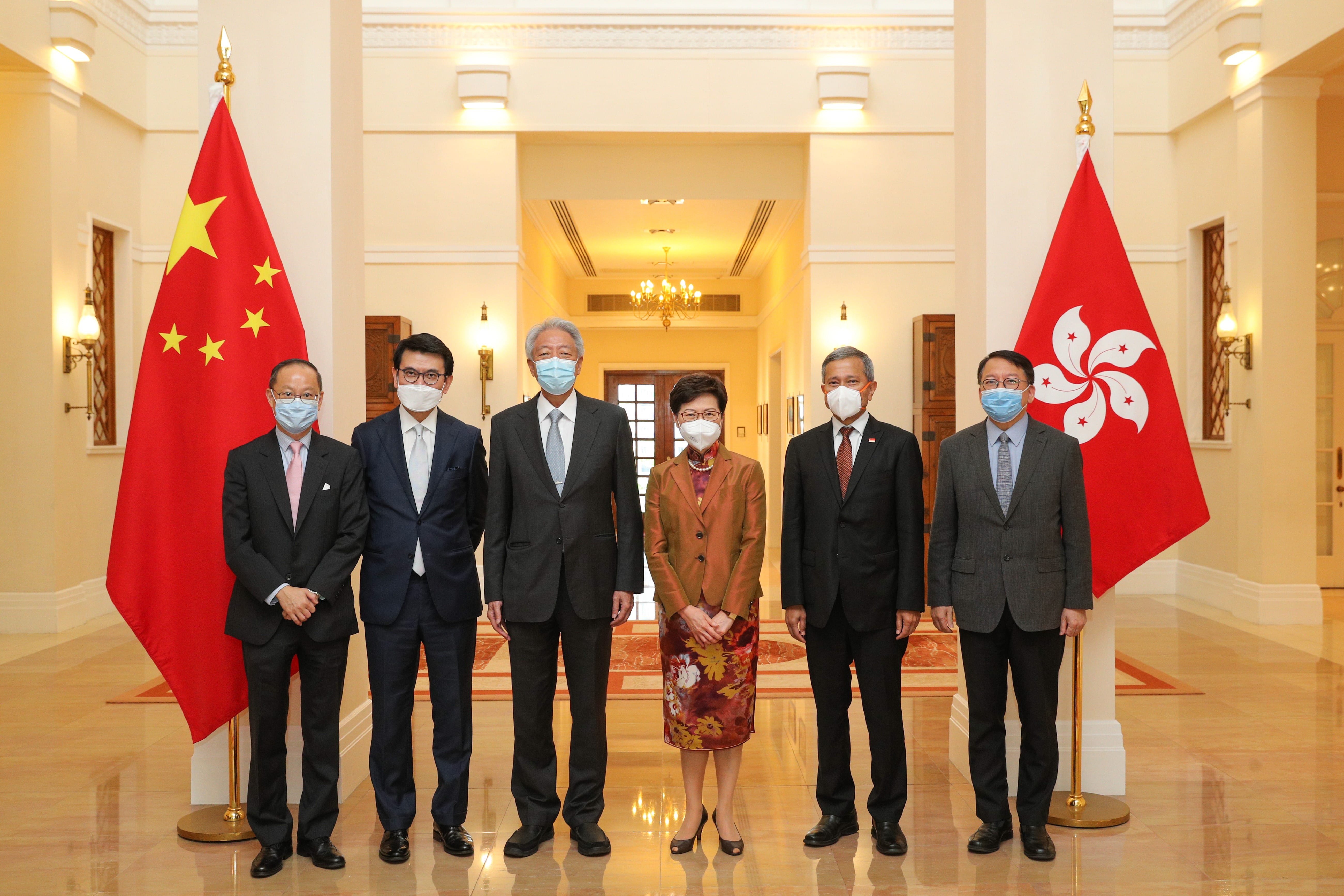 Two men in suits shake hands before flags of Singapore, Austria, and the European Union.